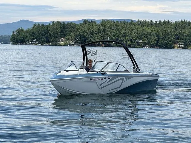 Slide: The Image of 2019 Tigé R21 boat cruising on a scenic lake with forested shoreline. - 13