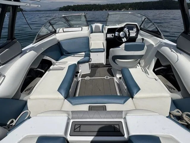 Slide: The Image of 2019 Tigé R21 boat interior with blue and white seating on a calm lake. - 18