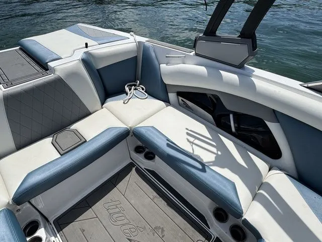 Slide: The Image of 2019 Tigé R21 boat interior with blue and white seating, cup holders, and lake view. - 21