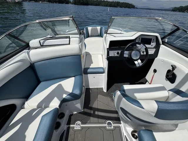 Slide: The Image of 2019 Tigé R21 boat interior with blue and white seating, steering wheel, and dashboard on a lake. - 22