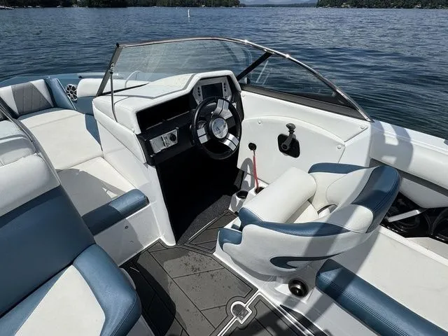 Slide: The Image of 2019 Tigé R21 boat interior with blue and white seating on a sunny lake. - 24