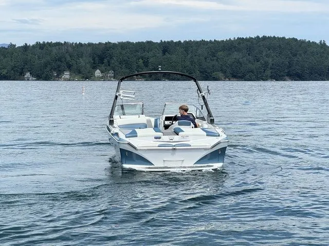 Slide: The Image of 2019 Tigé R21 boat cruising on a lake with forested shoreline. - 8