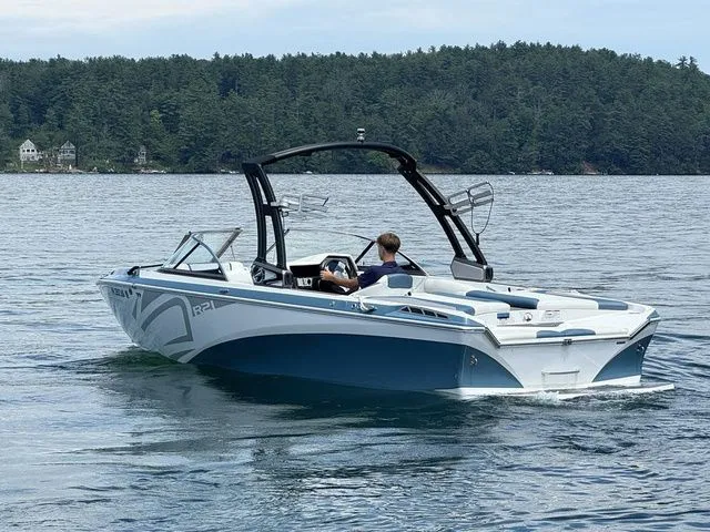 Slide: The Image of 2019 Tigé R21 boat cruising on a lake with forested shoreline. - 9