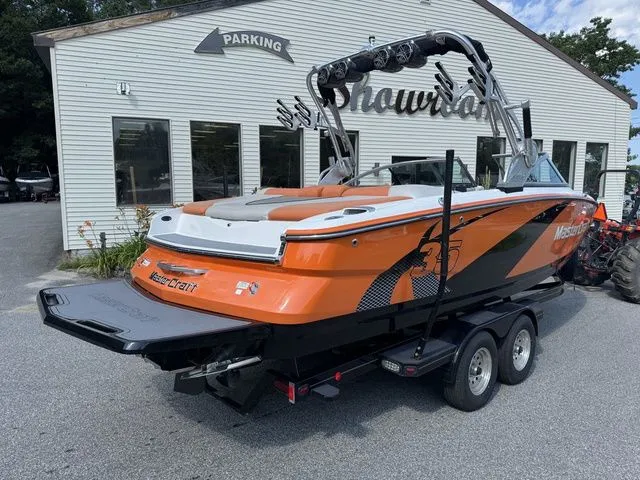 Slide: The Image of 2012 MasterCraft X-35 boat in orange and black on a trailer, parked outside a building. - 16