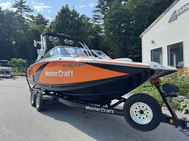 Slide: The Image of 2012 MasterCraft X-35 boat on trailer, orange and black, parked outdoors. - 17