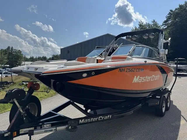 Slide: The Image of 2012 MasterCraft X-35 boat on trailer, orange and black design, parked outdoors. - 18