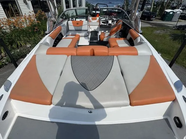 Slide: The Image of 2012 MasterCraft X-35 boat with orange and gray seating, docked near a waterfront. - 24