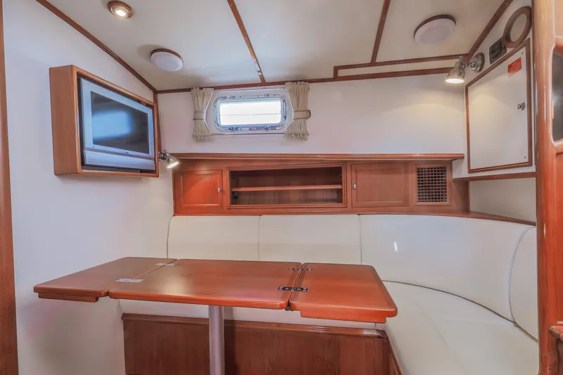 Slide: The Image of 2005 Grand Banks Eastbay 43 HX interior with cozy seating, wooden table, and mounted TV. - 22