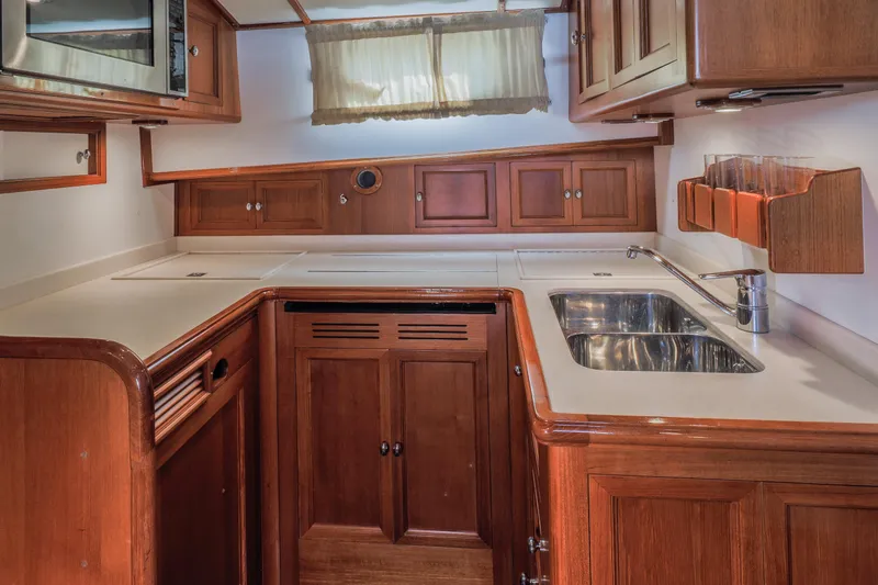 Slide: The Image of Luxurious 2005 Grand Banks Eastbay 43 HX yacht kitchen with wood cabinetry and stainless steel sink. - 23