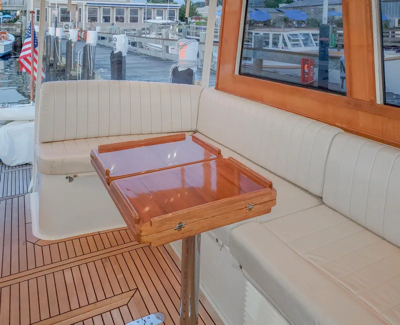 Slide: The Image of 2005 Grand Banks Eastbay 43 HX yacht interior with wooden table and cushioned seating. - 7