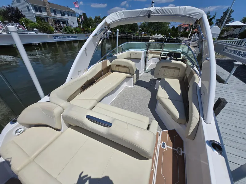 Slide: The Image of 2019 Regal 26 OBX boat with spacious seating, docked near waterfront homes. - 2