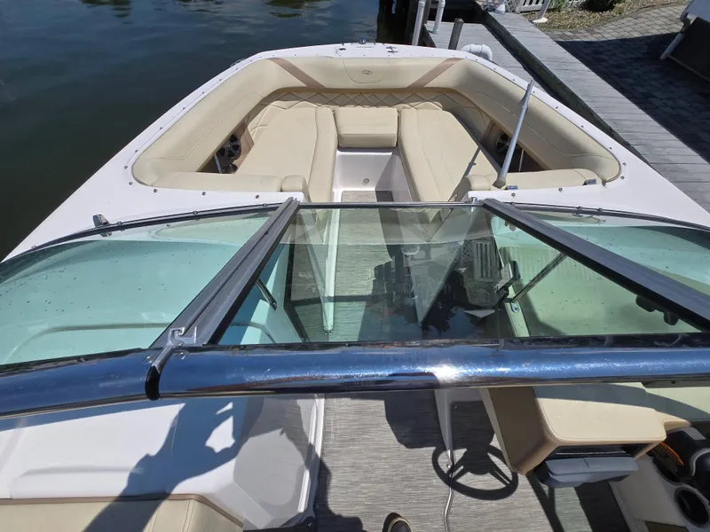 Slide: The Image of 2019 Regal 26 OBX boat with beige seating and glass windshield, docked by the water. - 4