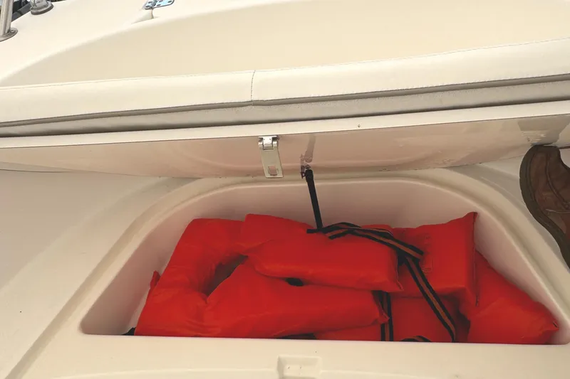 Slide: The Image of Storage compartment with orange life jackets on a 1999 Boston Whaler 21 Outrage boat. - 16