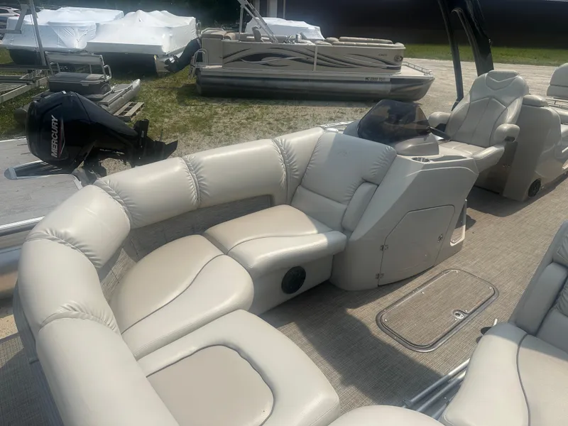 Slide: The Image of 2016 Manitou 25 Legacy SRS pontoon boat with beige seating and Mercury outboard motor. - 12