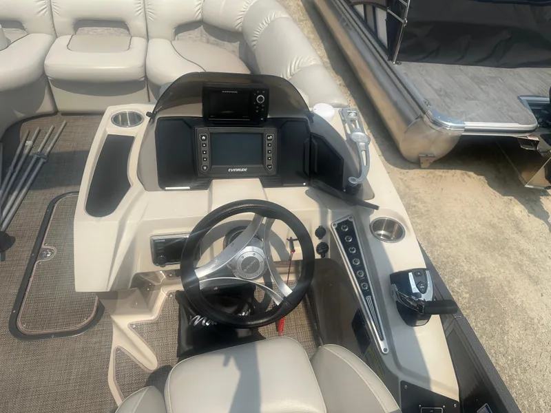 Slide: The Image of 2016 Manitou 25 Legacy SRS boat dashboard with steering wheel and control panel. - 17