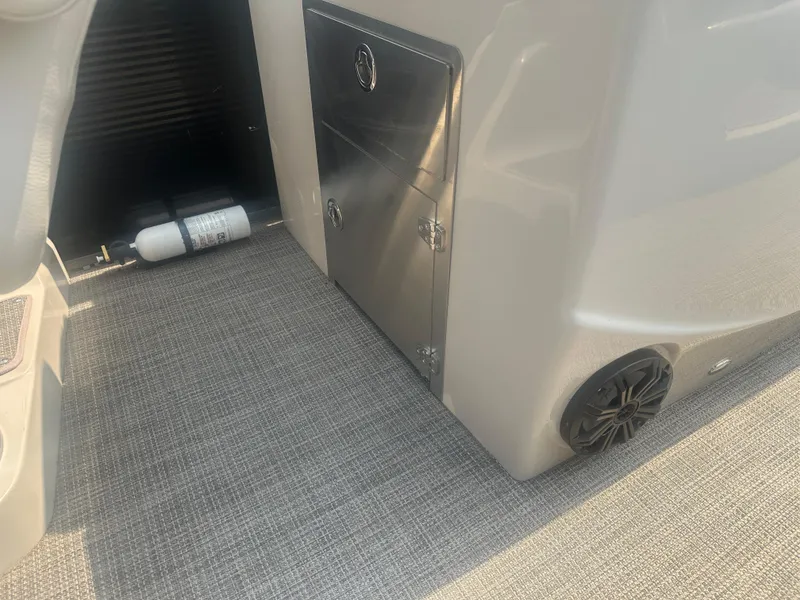 Slide: The Image of 2016 Manitou 25 Legacy SRS interior with storage compartment and speaker. - 23