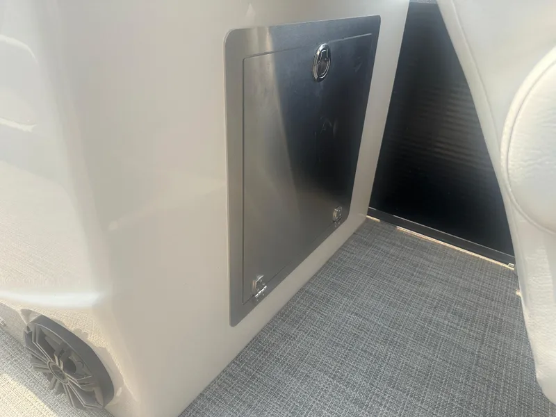 Slide: The Image of 2016 Manitou 25 Legacy SRS interior storage compartment with speaker and carpeted floor. - 24