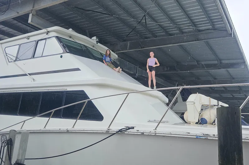 Slide: The Image of 2001 Darling Yachts 62 Enclosed Bridge with two people on deck under a metal roof. - 3