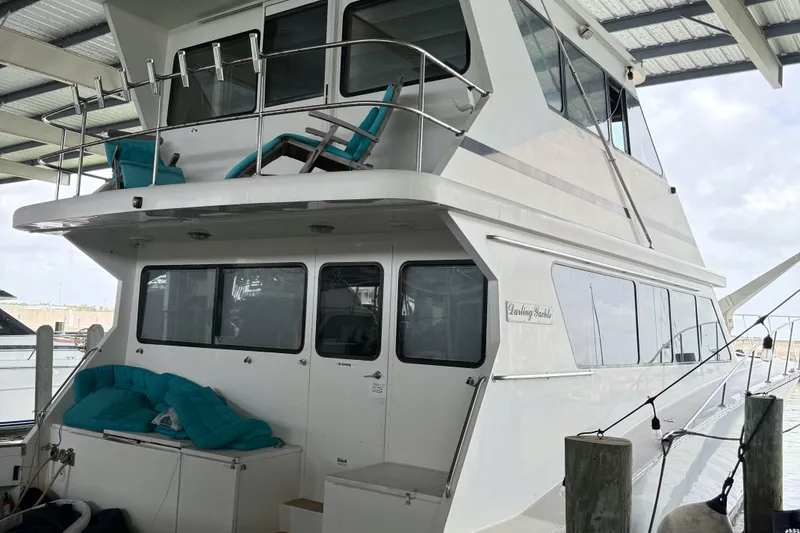 Slide: The Image of 2001 Darling Yachts 62 Enclosed Bridge docked, featuring upper deck seating and sleek design. - 4