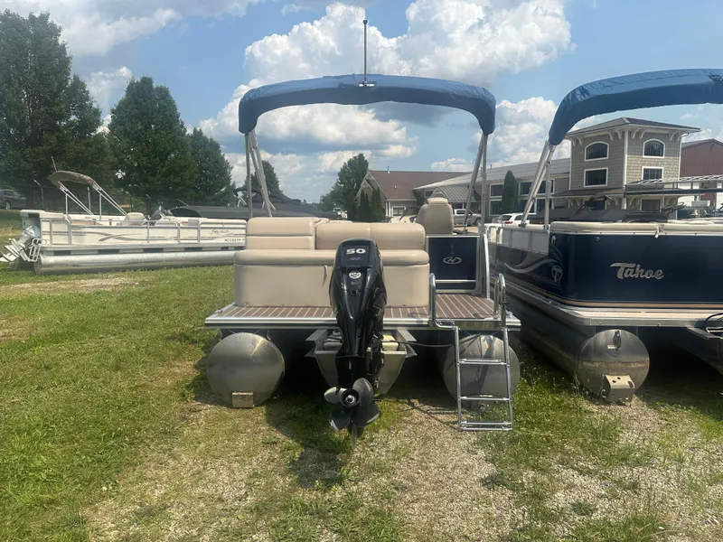 Slide: The Image of 2017 Harris Sunliner 230 pontoon boat with outboard motor, parked on grass under a cloudy sky. - 3