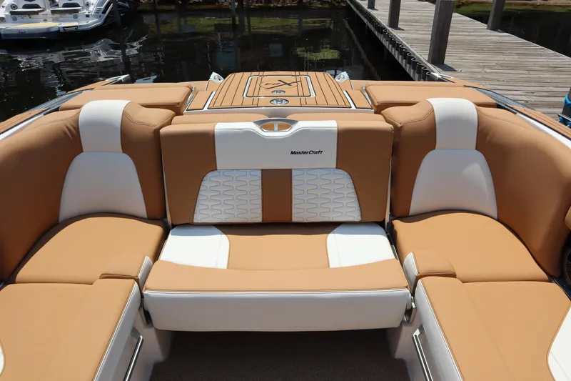 Slide: The Image of 2020 MasterCraft X24 boat interior with tan and white seating, dockside view. - 12