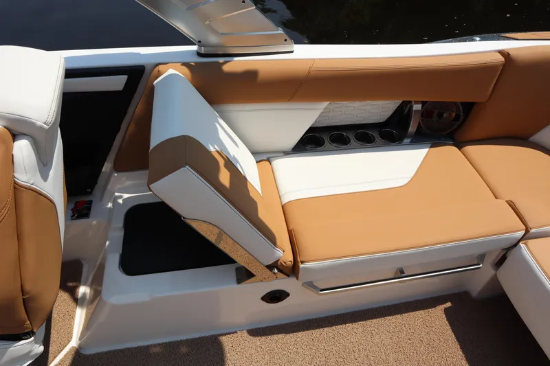 Slide: The Image of 2020 MasterCraft X24 boat interior with tan and white seating, cup holders, and storage compartment. - 14