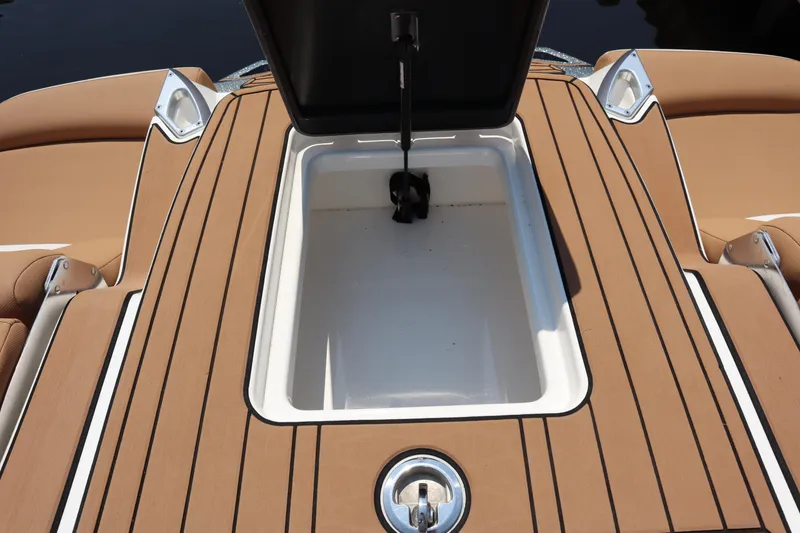 Slide: The Image of 2020 MasterCraft X24 boat storage compartment with open lid, featuring teak-style decking. - 17