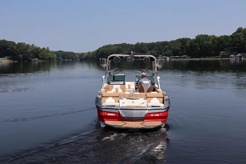 Slide: The Image of 2020 MasterCraft X24 boat cruising on a serene lake with lush green surroundings. - 3