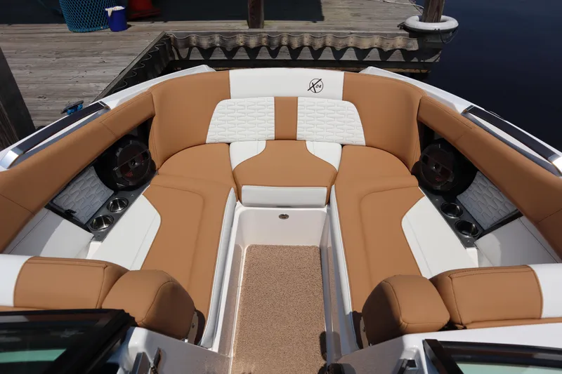 Slide: The Image of 2020 MasterCraft X24 boat interior with tan and white seating, docked by wooden pier. - 4