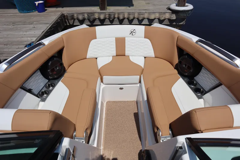 Slide: The Image of 2020 MasterCraft X24 boat interior with tan and white seating, cup holders, and speakers. - 5