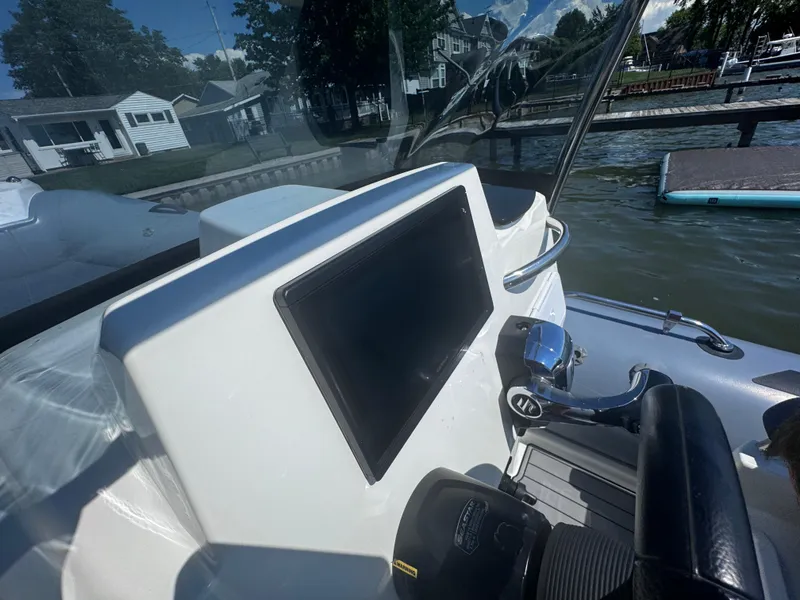 Slide: The Image of 2022 Brig Eagle 6 boat dashboard with controls, docked by a lakeside. - 16