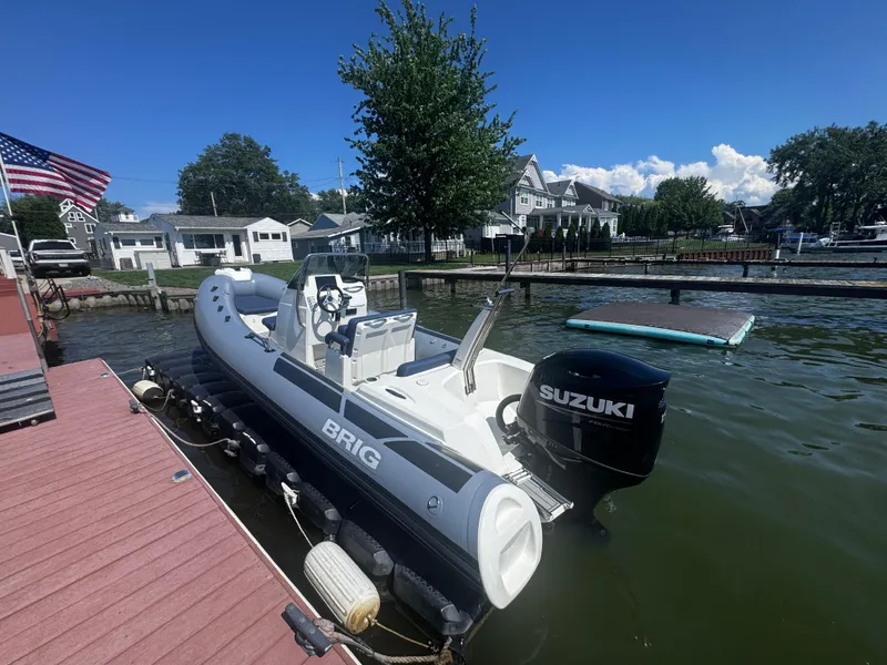 Slide: The Image of 2022 Brig Eagle 6 boat docked with Suzuki outboard motor, American flag nearby. - 30