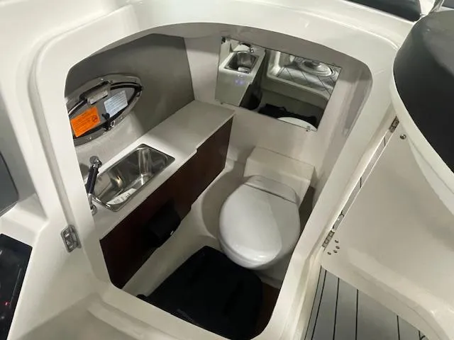 Slide: The Image of 2025 Chaparral 26 Surf boat interior with compact bathroom and sink. - 11