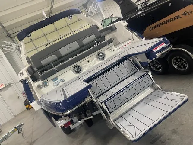 Slide: The Image of 2025 Chaparral 26 Surf boat with extended swim platform and seating in a showroom. - 17