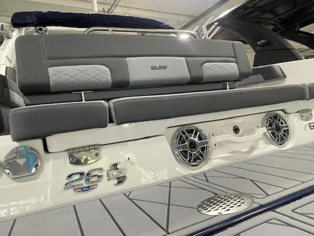 Slide: The Image of 2025 Chaparral 26 Surf boat rear view with speakers and cushioned seating. - 18