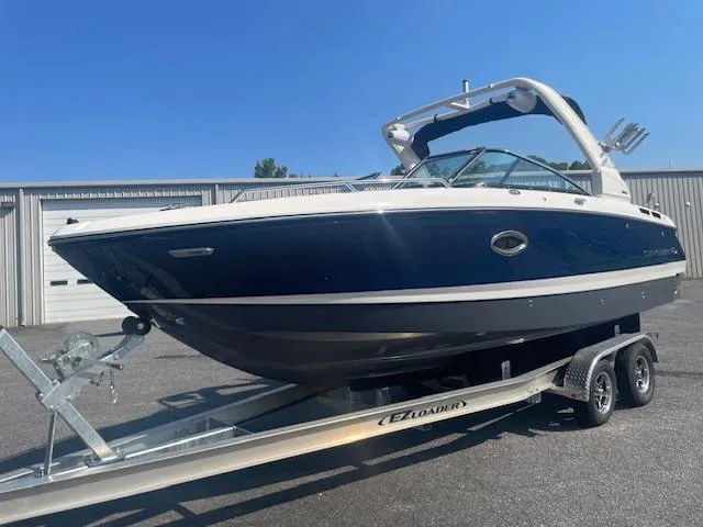 Slide: The Image of 2025 Chaparral 26 Surf boat on trailer, parked outdoors. - 2