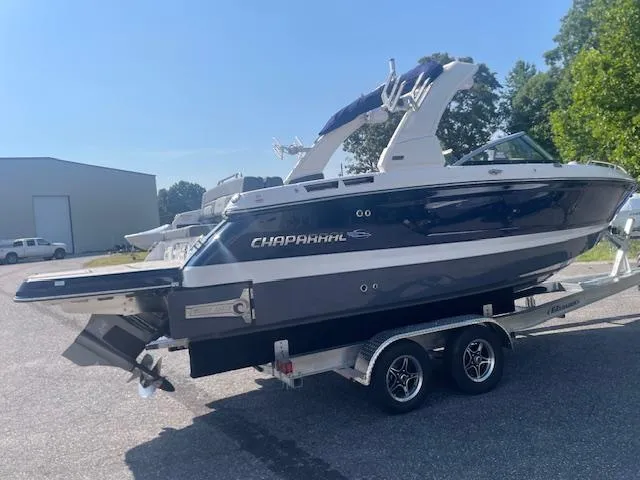Slide: The Image of 2025 Chaparral 26 Surf boat on trailer, blue and white design, parked outdoors. - 3