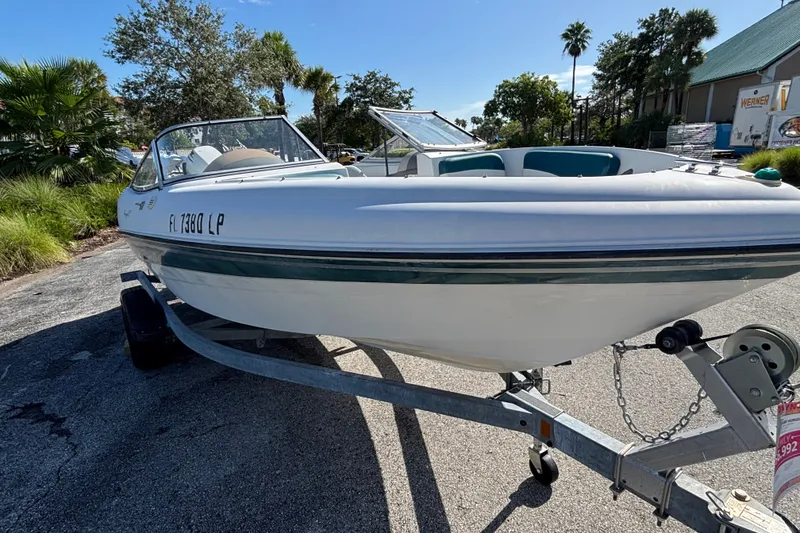 Slide: The Image of 2001 Four Winns 180 Horizon boat on trailer, parked outdoors with trees in background. - 1