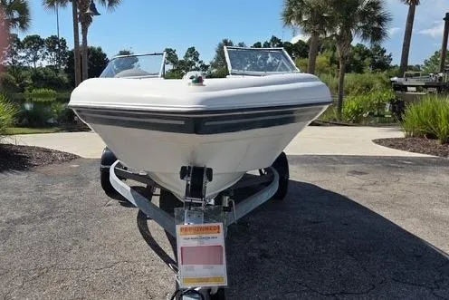 Slide: The Image of 2001 Four Winns 180 Horizon boat on trailer, parked outdoors with palm trees. - 2
