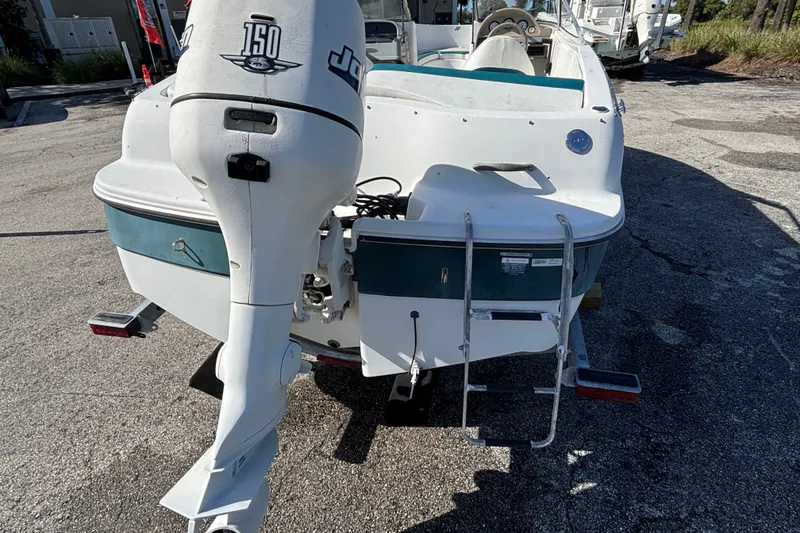 Slide: The Image of 2001 Four Winns 180 Horizon boat with outboard motor and swim ladder, parked on pavement. - 3
