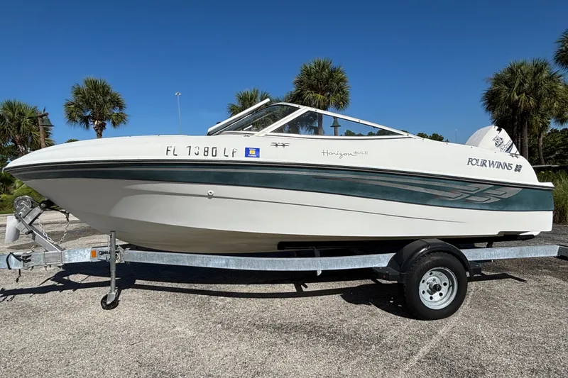 The Image of 2001 Four Winns 180 Horizon boat on trailer, parked outdoors with palm trees in background. - 0