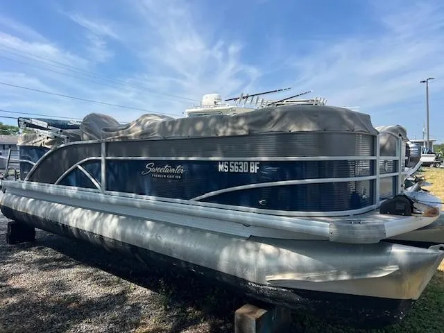Slide: The Image of 2016 Godfrey 242 Premiere pontoon boat with cover, parked outdoors under blue sky. - 10