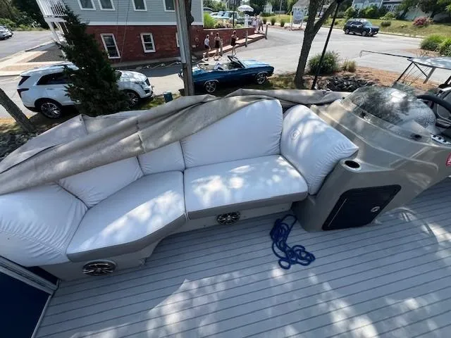 Slide: The Image of 2016 Godfrey 242 Premiere boat with white seating and covered deck, parked near vehicles. - 3
