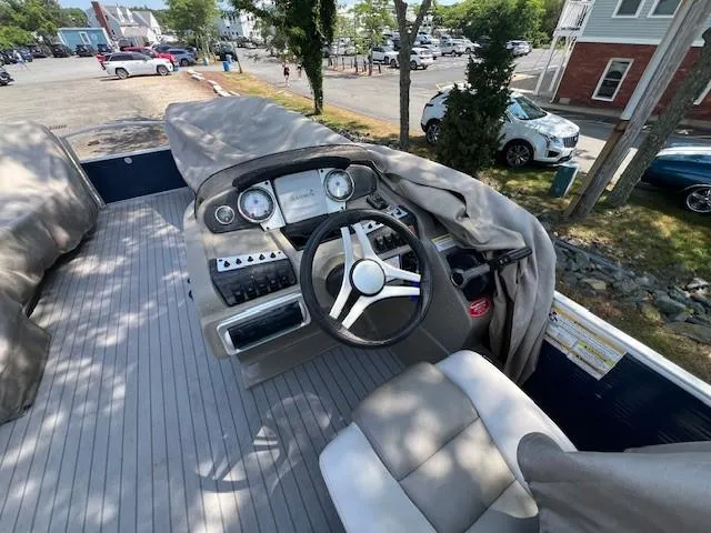 Slide: The Image of 2016 Godfrey 242 Premiere boat dashboard with steering wheel and covered seats. - 4