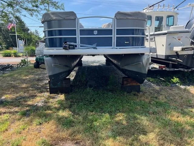 Slide: The Image of 2016 Godfrey 242 Premiere pontoon boat on grass, front view, with nearby boats. - 7