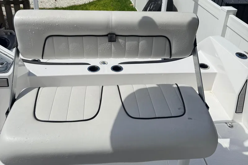Slide: The Image of 2023 Yamaha Boats 222 FSH Sport interior seating with cup holders, wet from recent use. - 11