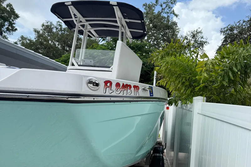 Slide: The Image of 2023 Yamaha Boats 222 FSH Sport in driveway, surrounded by greenery and white fence. - 13