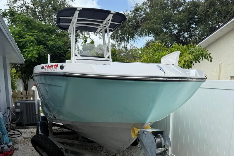 Slide: The Image of 2023 Yamaha Boats 222 FSH Sport on trailer, parked outdoors near trees and a house. - 14