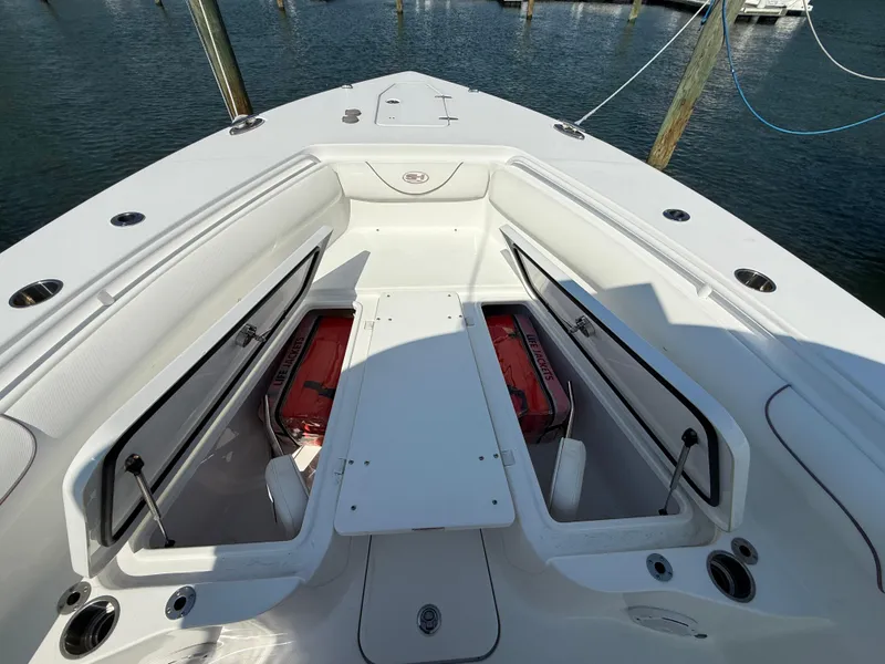 Slide: The Image of 2018 Sea Hunt Gamefish 30 Forward Seating with open storage compartments on a sunny day. - 23