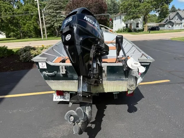 Slide: The Image of 1999 Lund SSV-16 Tiller boat with Mercury 25 outboard motor, parked on asphalt. - 7